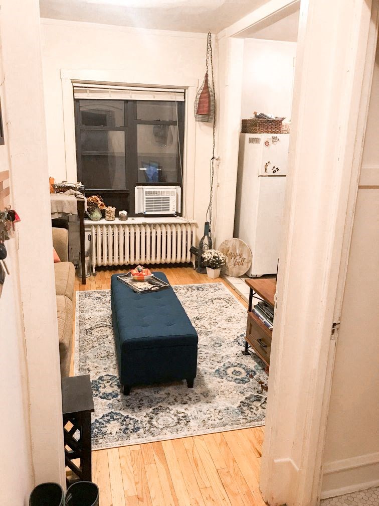 a living room with a blue ottoman in front of a window