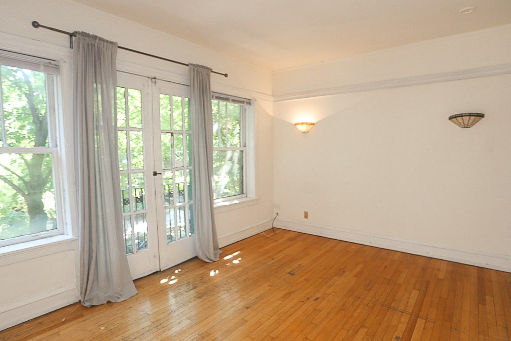 an empty living room with white walls and wood floors and a window with curtains