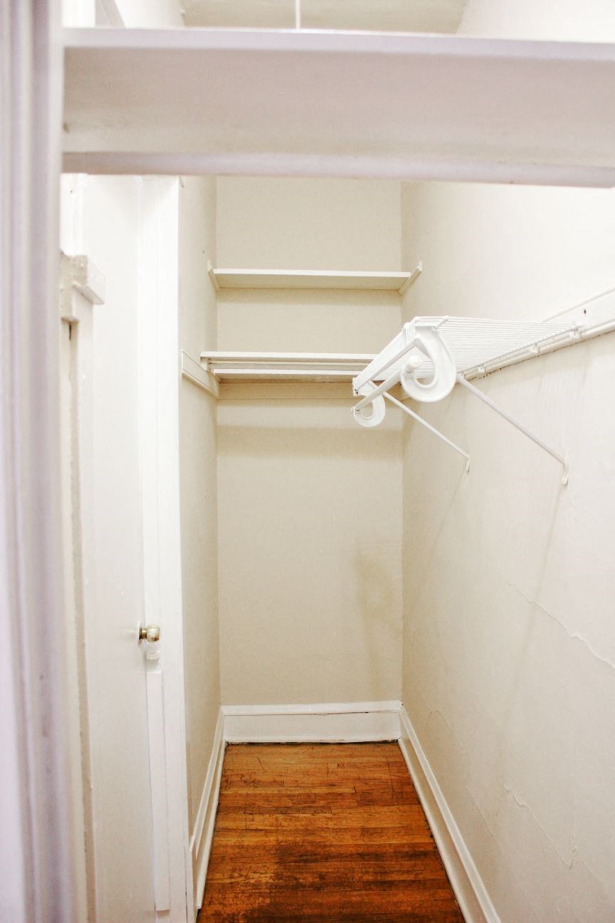 a walk in closet with white shelves and a white closet door