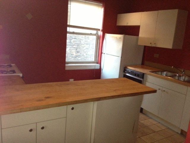 a kitchen with white cabinets and a wooden counter top