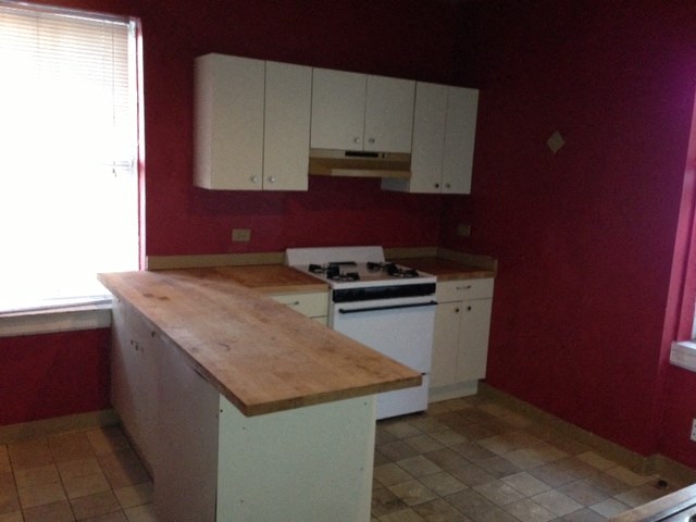 an empty kitchen with red walls and white cabinets