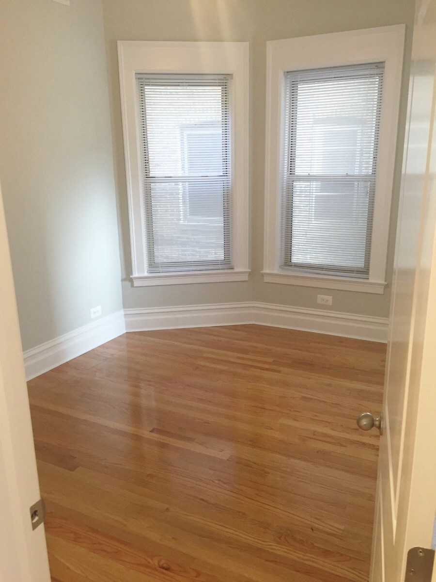 a living room with a hard wood floor and three windows