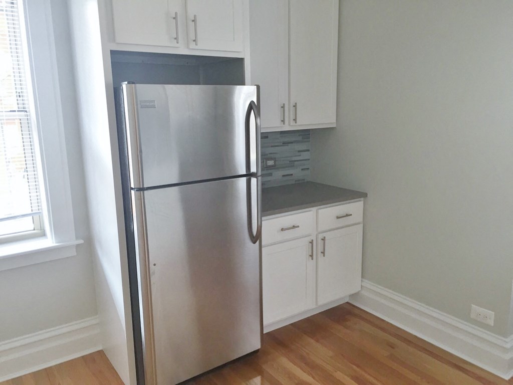 a kitchen with a stainless steel refrigerator and white cabinets