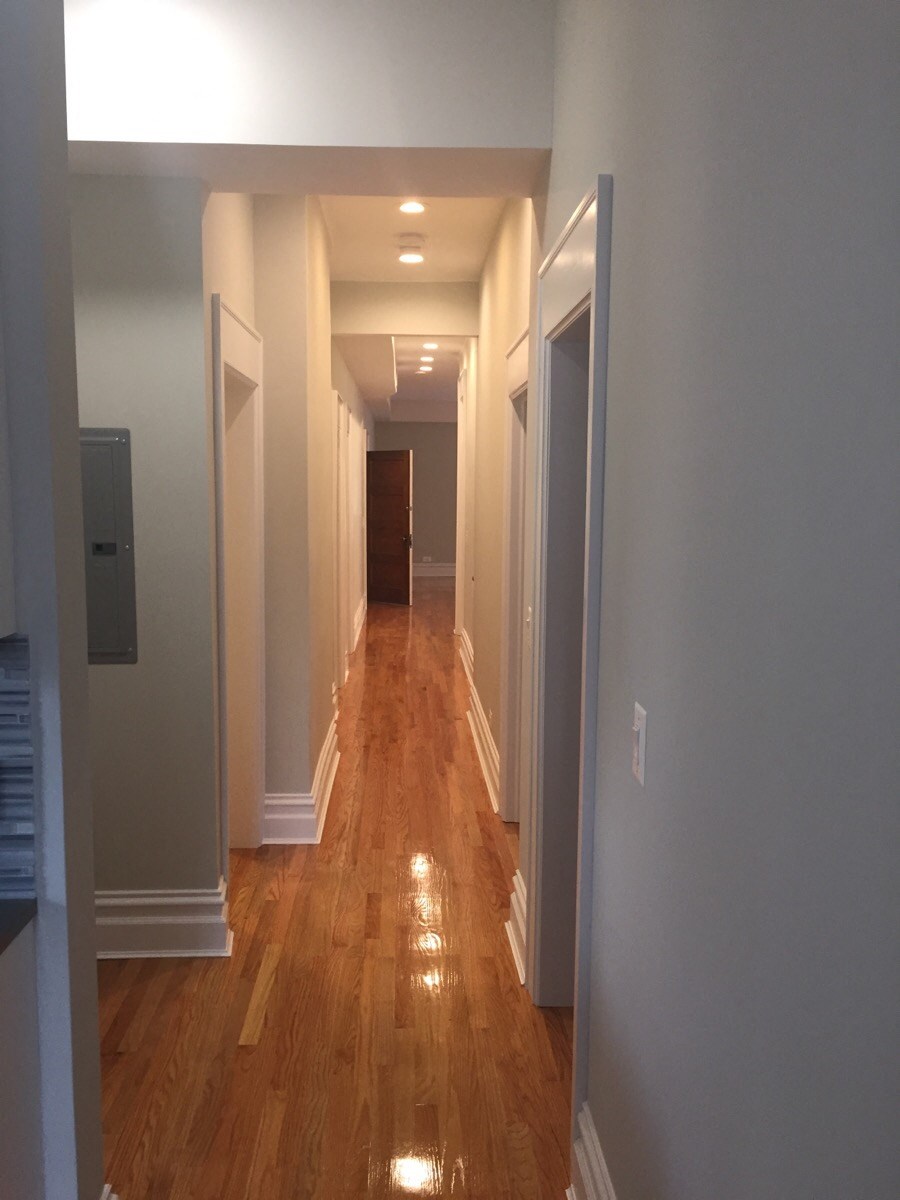 a look down the hallway of a renovated house with wood floors and grey walls