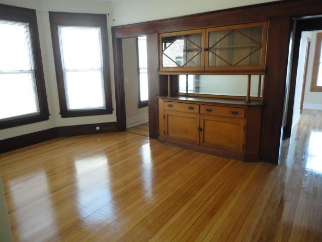 an empty living room with a wooden floor and a hutch