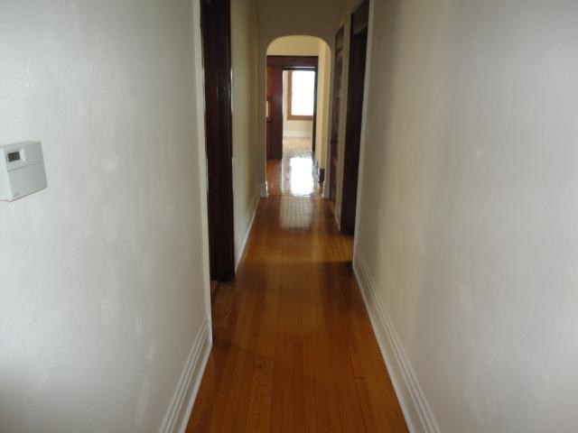 a hallway with a wood floor and white walls