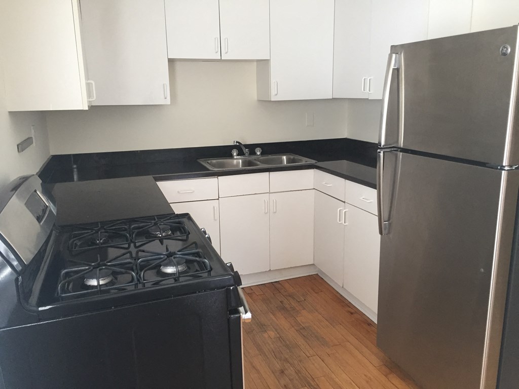 an empty kitchen with white cabinets and a stove and refrigerator