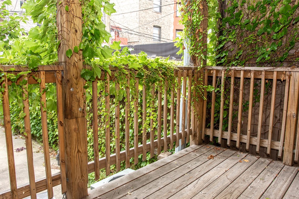 a backyard deck with a wooden fence and plants on it