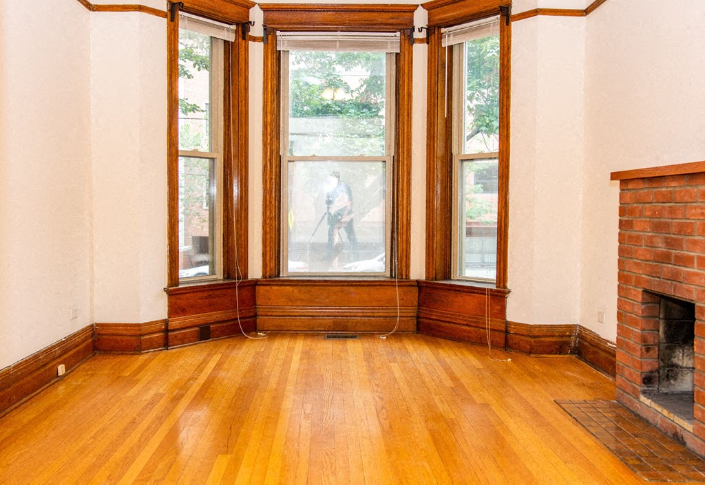 an empty living room with a fireplace and wooden floors