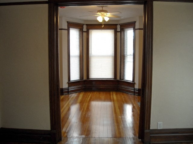 an empty room with a ceiling fan and three windows
