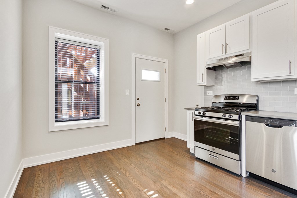 a kitchen with white cabinets and a stove and a window