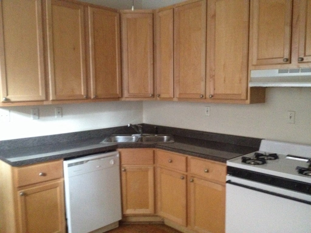an empty kitchen with wooden cabinets and white appliances