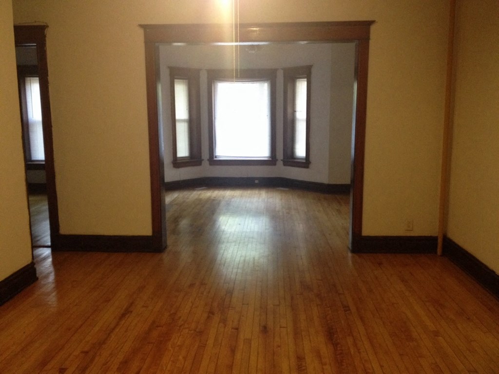 an empty living room with wooden floors and windows
