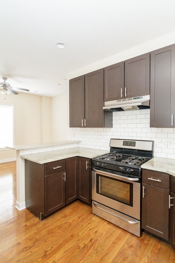 an empty kitchen with wooden floors and stainless steel appliances