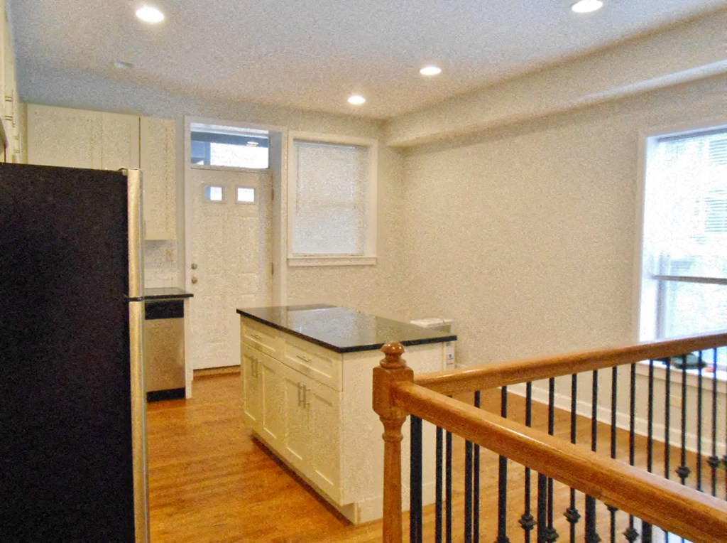 a large kitchen with a staircase and a refrigerator