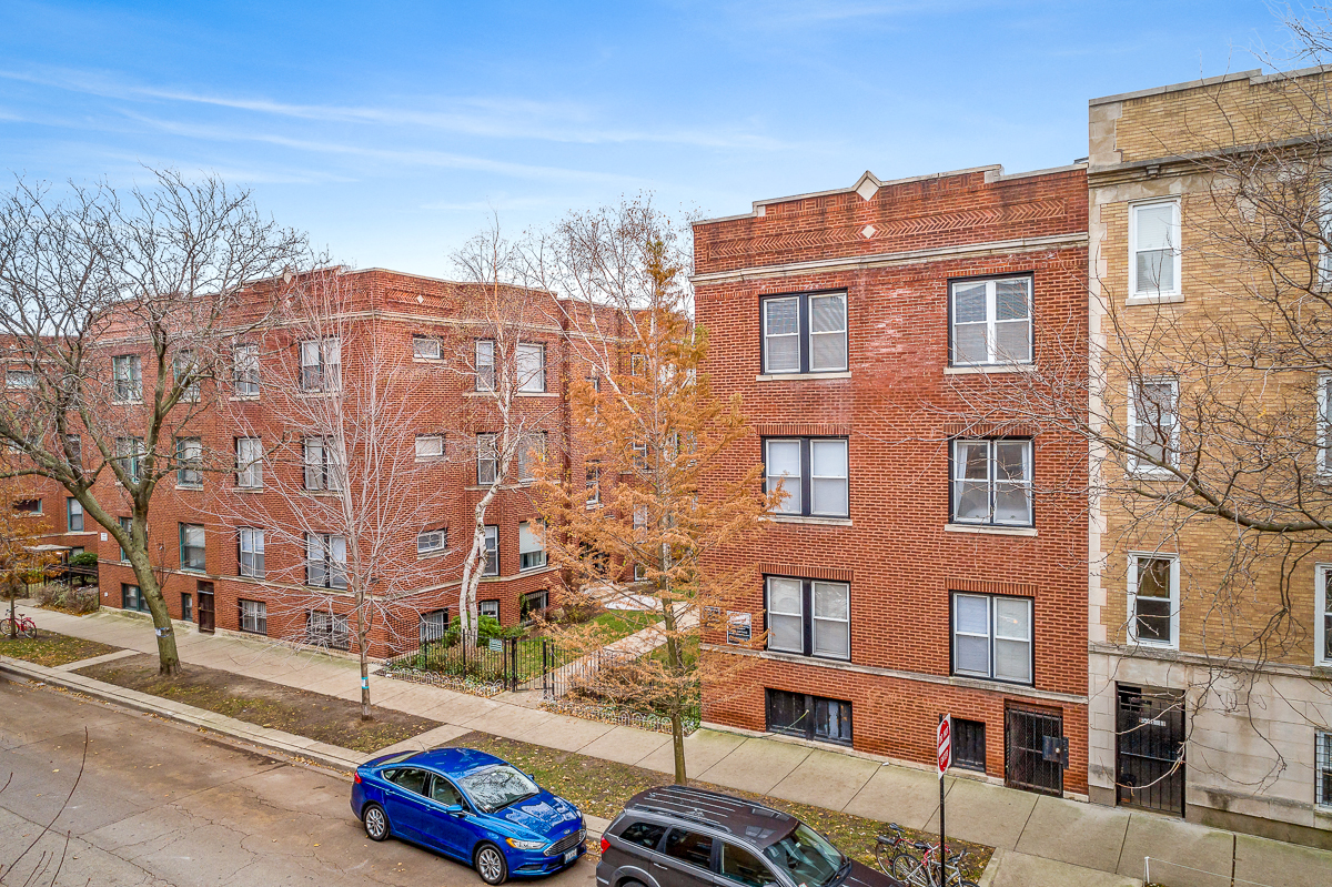 a view of a red brick building with cars parked in front of it