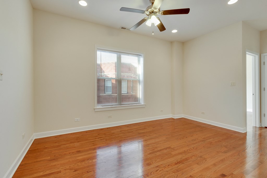 an empty living room with wood floors and a ceiling fan