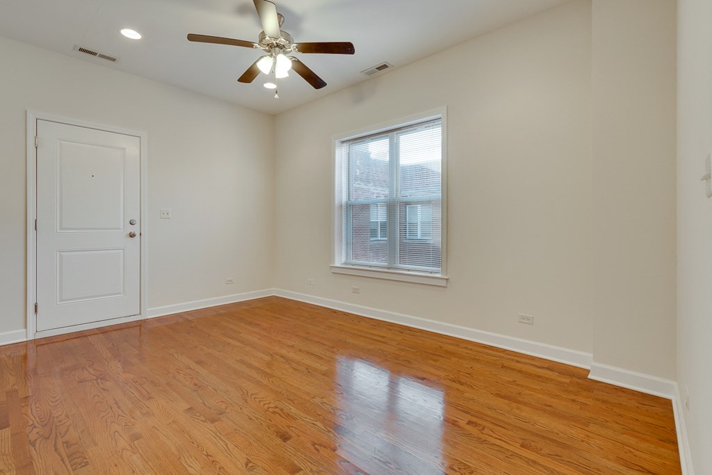 an empty living room with wood floors and a ceiling fan