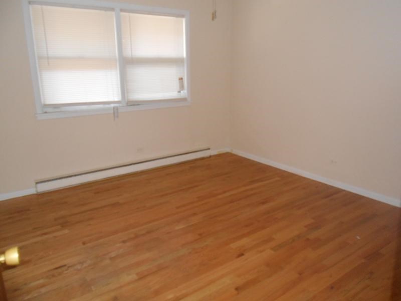 an empty room with a wooden floor and two windows