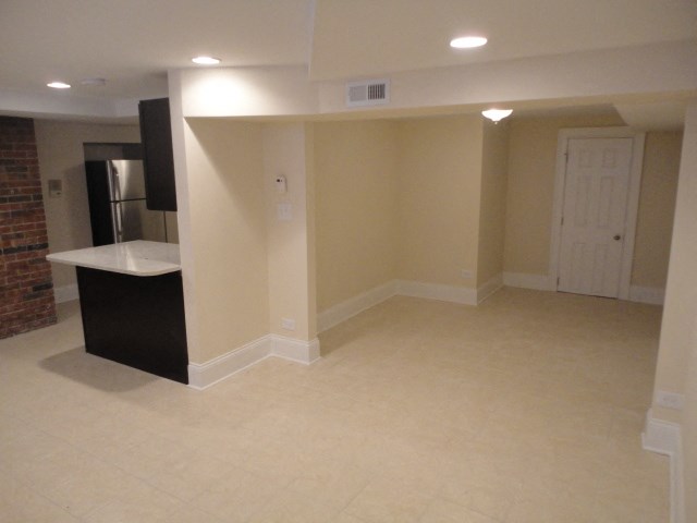 an empty living room with a refrigerator and a sink