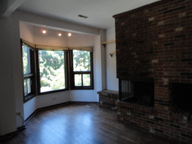 an empty living room with a fireplace and large windows
