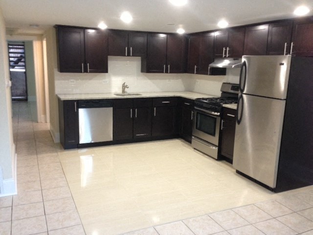 an empty kitchen with black cabinets and stainless steel appliances
