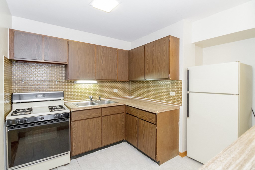 an empty kitchen with a stove refrigerator and sink