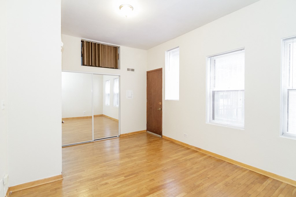 an empty living room with wood floors and white walls