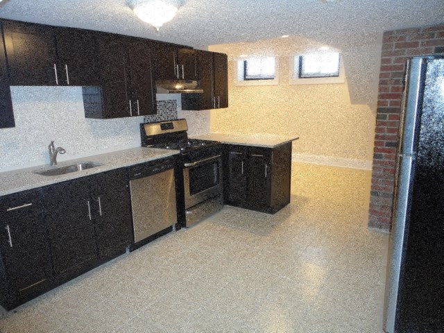 an empty kitchen with black cabinets and a sink