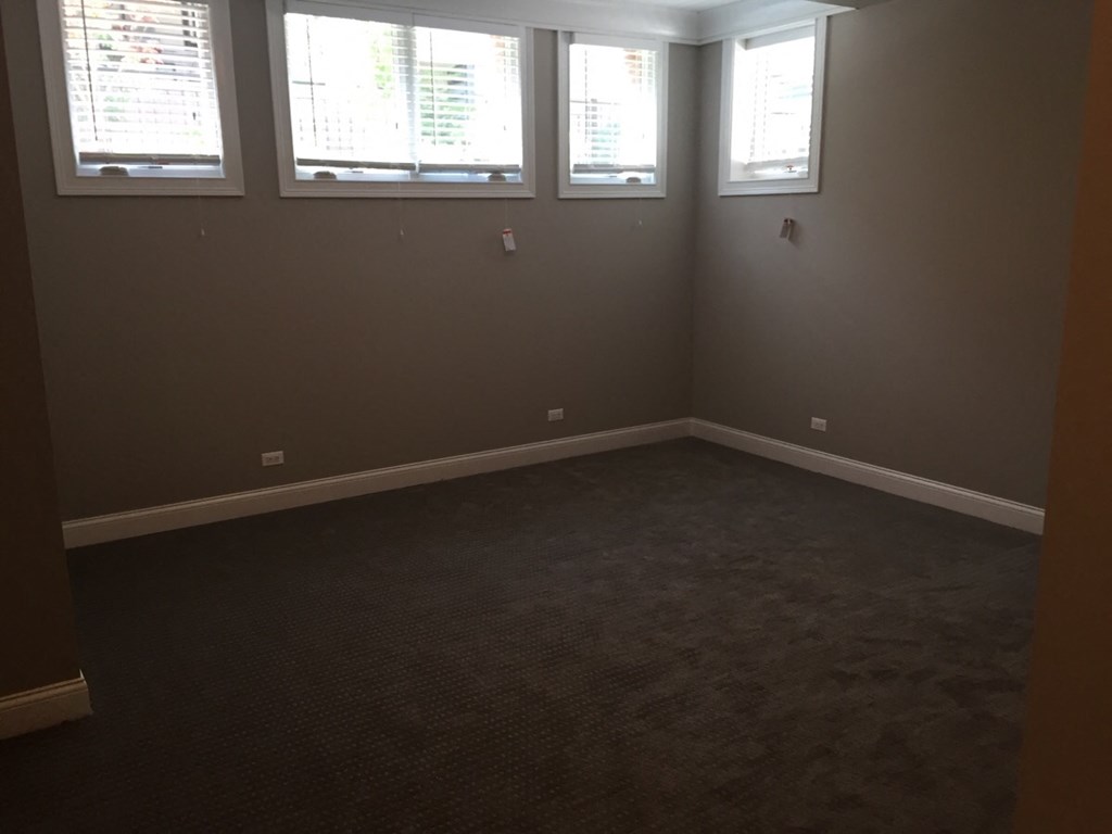 an empty room with three windows and a carpet
