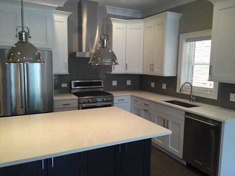 a kitchen with a white counter top and a stainless steel refrigerator