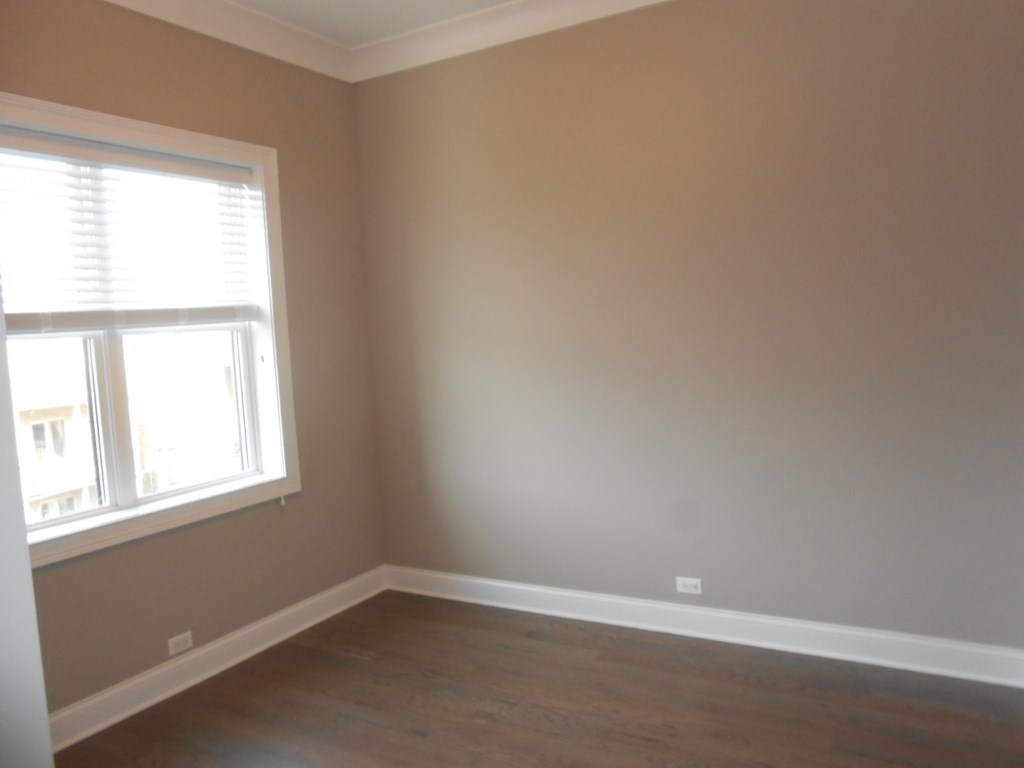 an empty room with a window and wooden floors