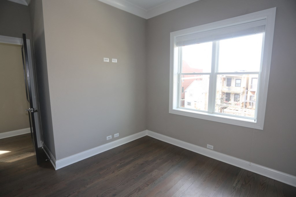 an empty room with a window and wooden floors