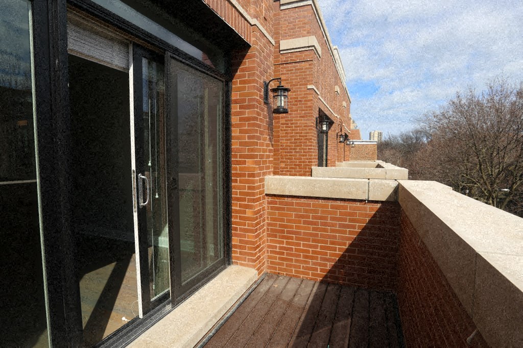 a balcony with a brick wall and a glass door