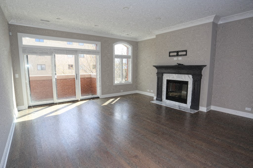 an empty living room with a fireplace and wood floors