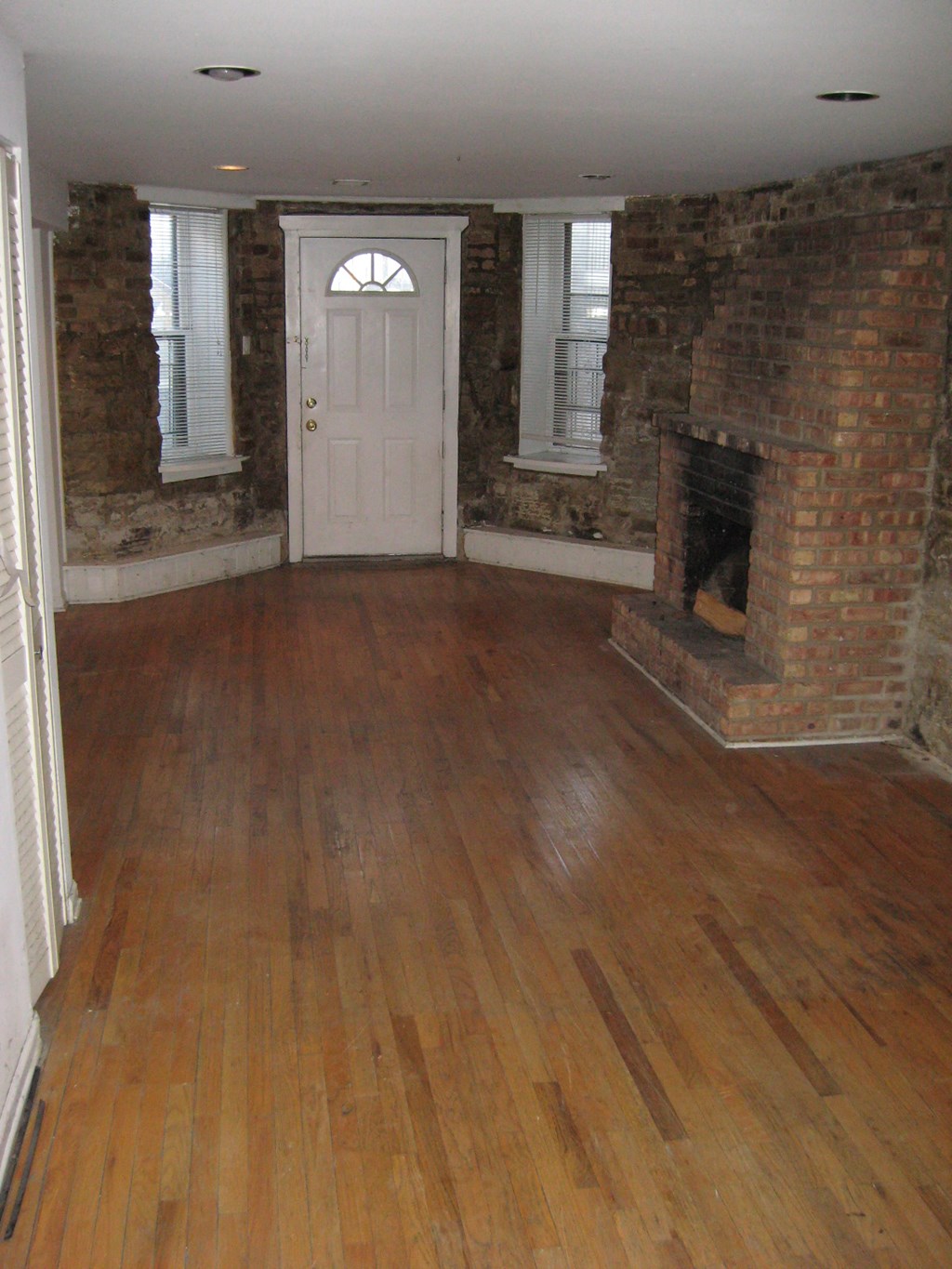 an empty living room with a fireplace and wooden floors