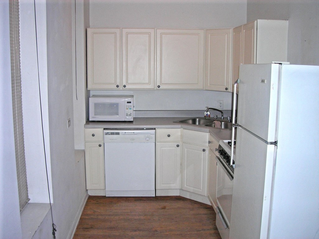 a kitchen with white cabinets and appliances and a refrigerator
