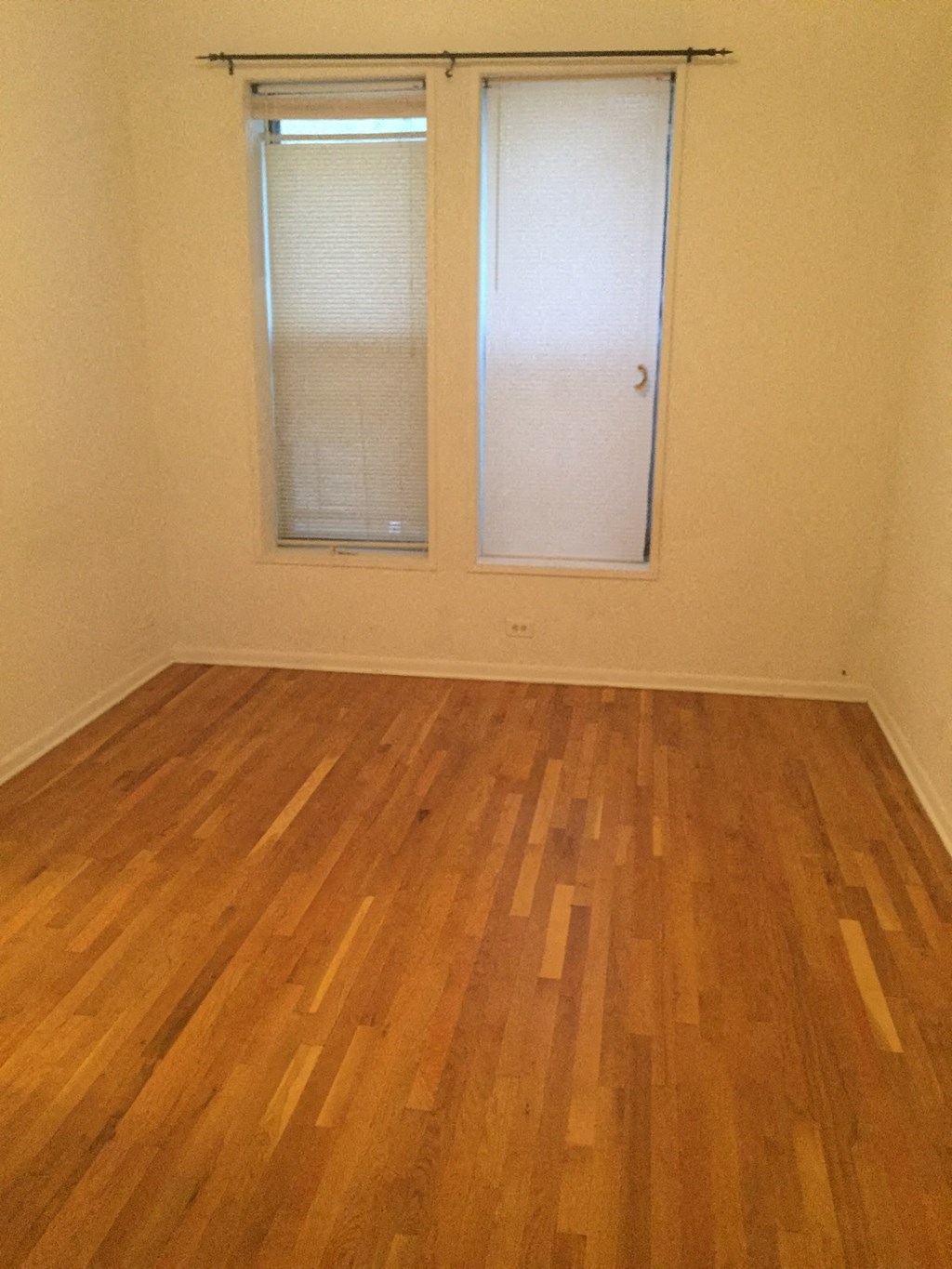 an empty room with a wood floor and two windows
