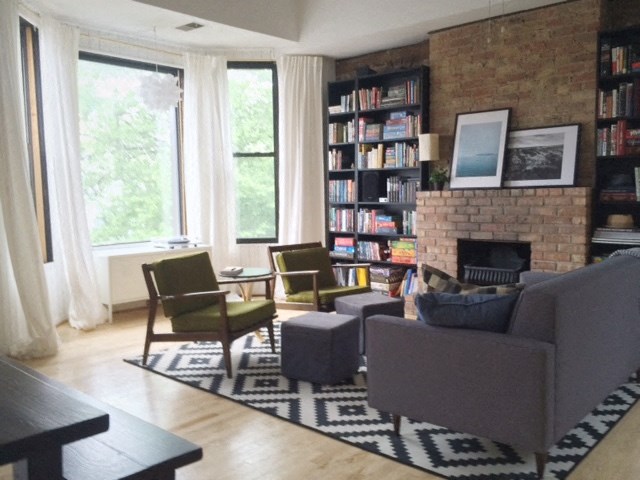 a living room with couches and chairs and a brick fireplace