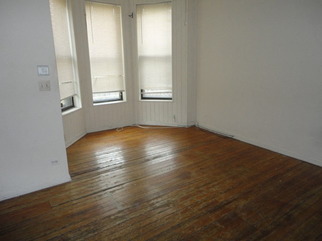 a living room with a wood floor and three windows