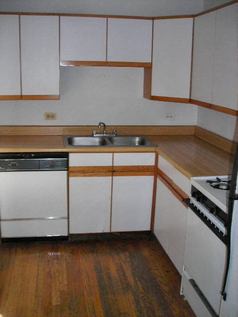 an empty kitchen with white cabinets and a sink