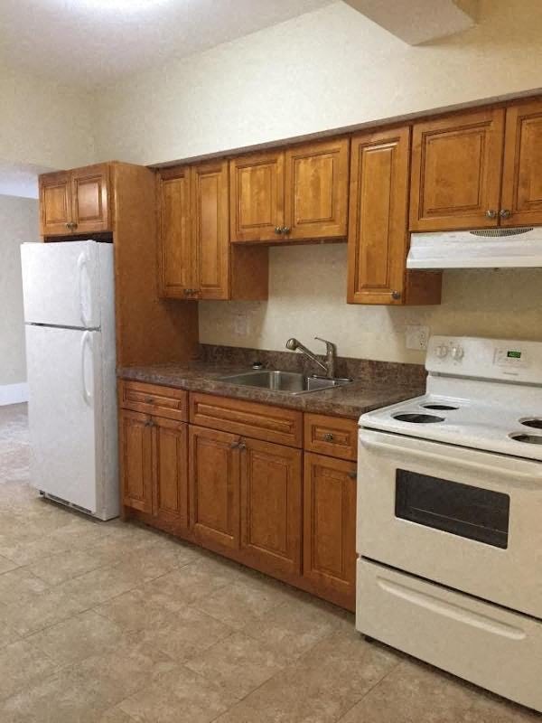 a kitchen with white appliances and wooden cabinets