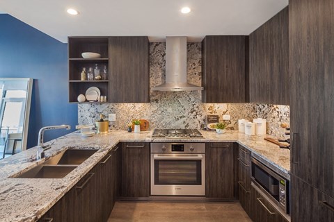 A modern kitchen with dark wood cabinets and a marble countertop.