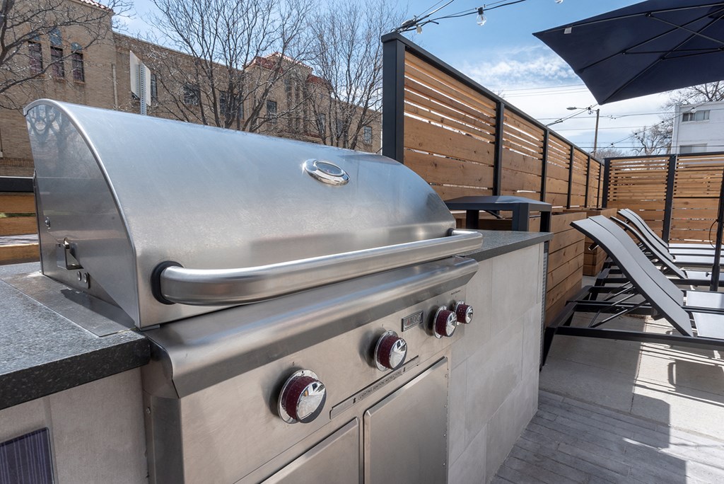 a stainless steel barbecue grill on a patio with an umbrella