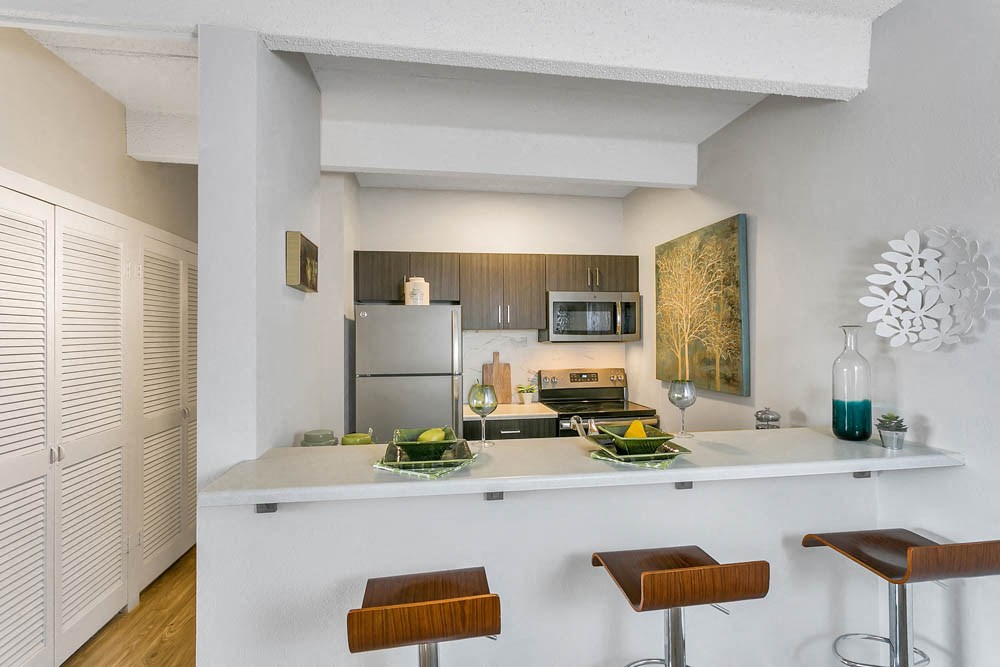 a kitchen with a bar and a stainless steel refrigerator