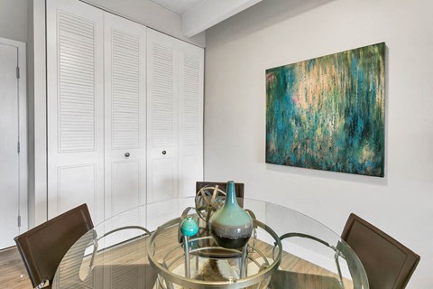 a dining room with a glass table and a painting on the wall