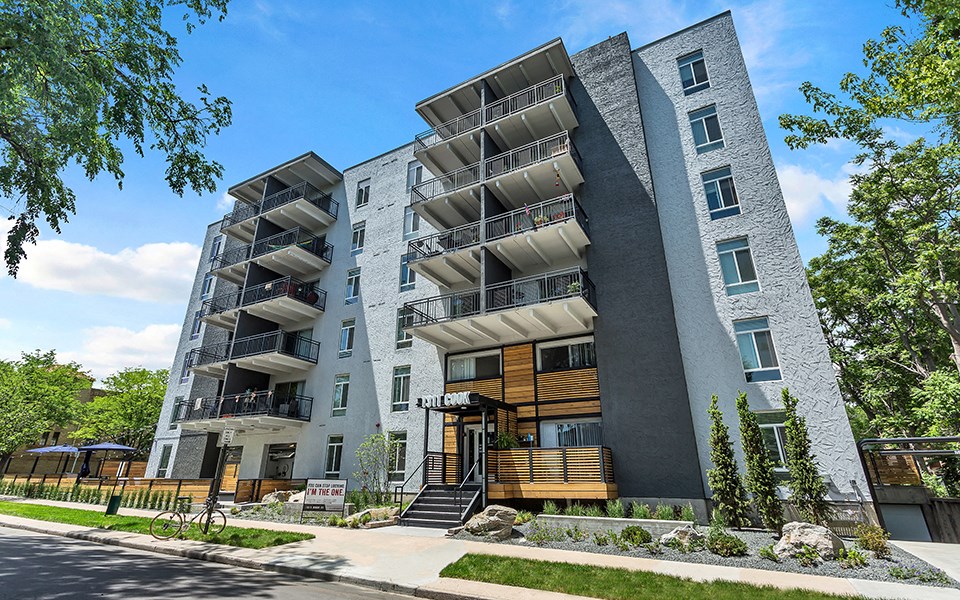 a grey apartment building with balconies and a sidewalk