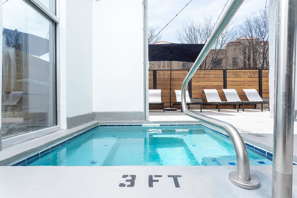 a small pool next to a window with two chairs