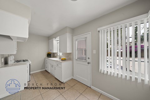 A kitchen with white cabinets and a logo for Beach Front Property Management.
