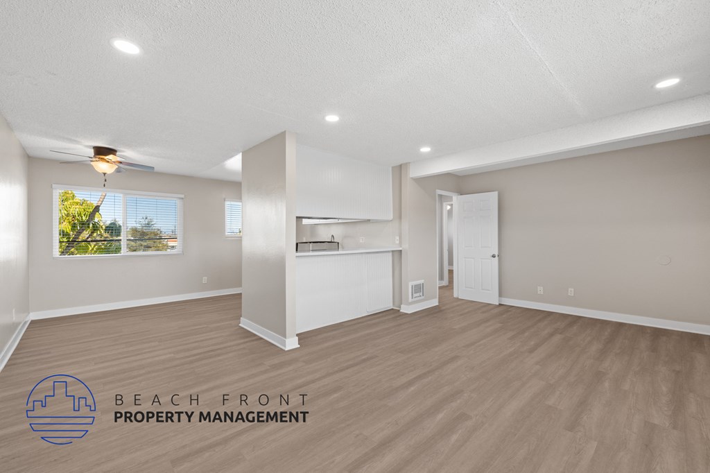 A spacious room with a ceiling fan and wooden flooring.